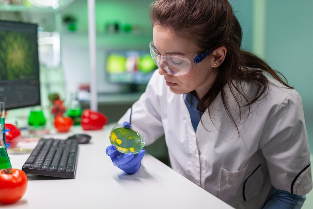 Scientist examining a petri dish in a lab.